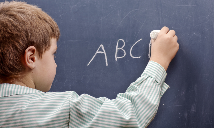 Boy writing ABCs on chalkboard