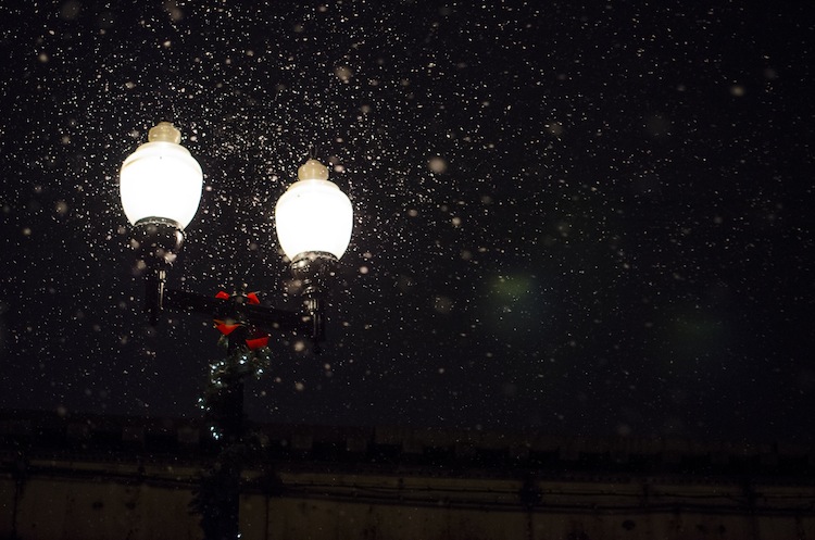 Old-fashioned streetlight with falling snow