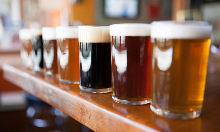 different beers in glasses lined up on a bar