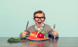 National Nutrition Month boy with glasses ready to eat his vegetables