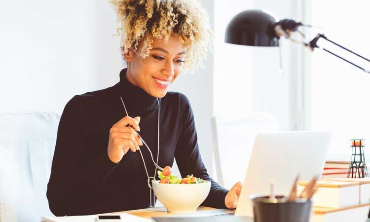 Enhance-Productivity-diet-tips woman eating lunch at her desk