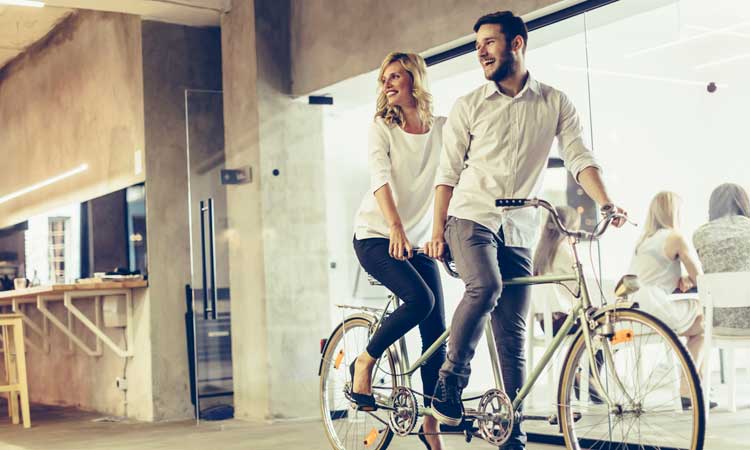 3-Evolving-Wellness-Trends riding tandem bicycle in office