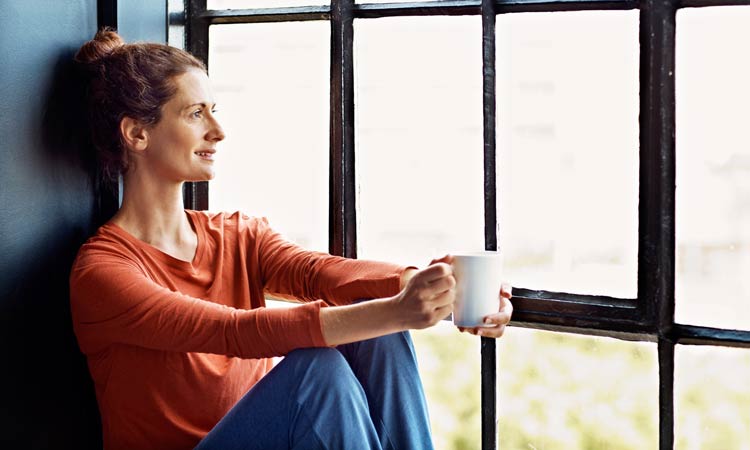 3-Ways-To-Balance-Your-Health-This-Fall-With-Ritual woman drinking tea by window