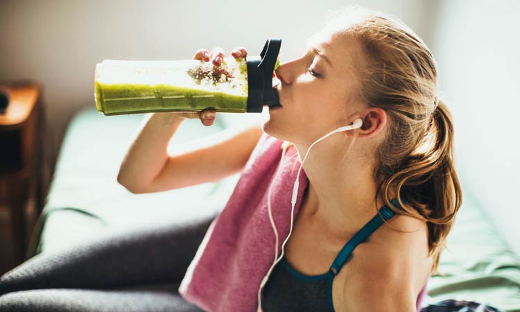 woman drinking a green juice