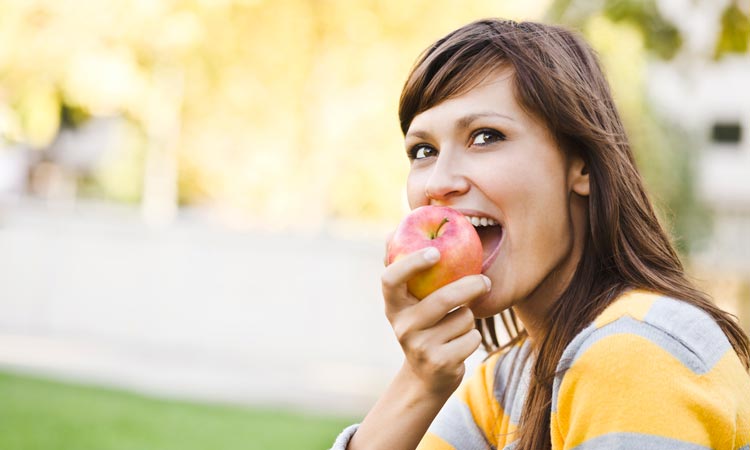 8-Foods-You-Should-Be-Buying-In-Season woman eating an apple