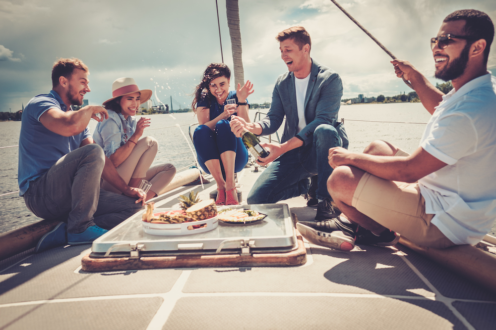 Happy friends eating fruits and drinking on a yacht